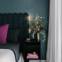 Moody, dark blue tone painted on bedroom walls creates for mysterious and luxurious space.
