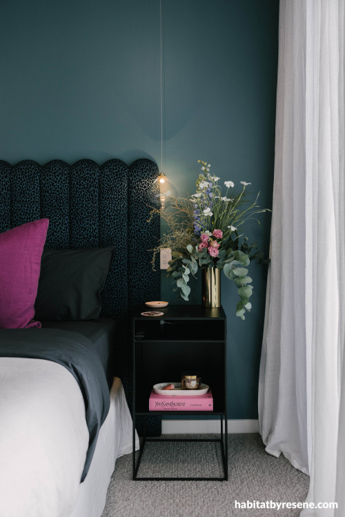 Moody, dark blue tone painted on bedroom walls creates for mysterious and luxurious space.