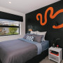 Feature wall painted in black colour topped with zesty orange pattern completes the room