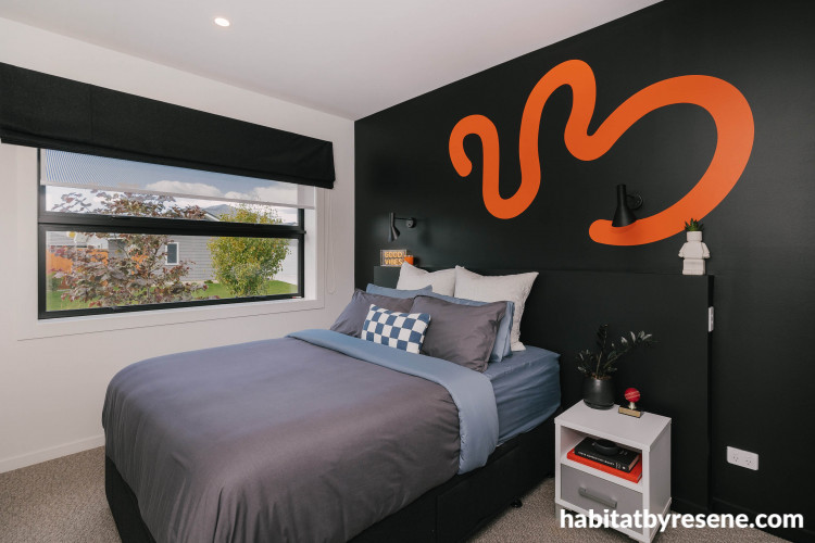 Feature wall painted in black colour topped with zesty orange pattern completes the room