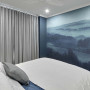 Wallpaper with blue & green tones transports bedroom to scenic hilltop 