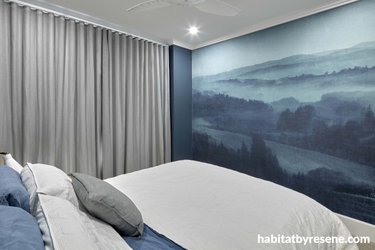 Wallpaper with blue & green tones transports bedroom to scenic hilltop 