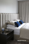 A neutral bedroom with soft drapes and blue pillows