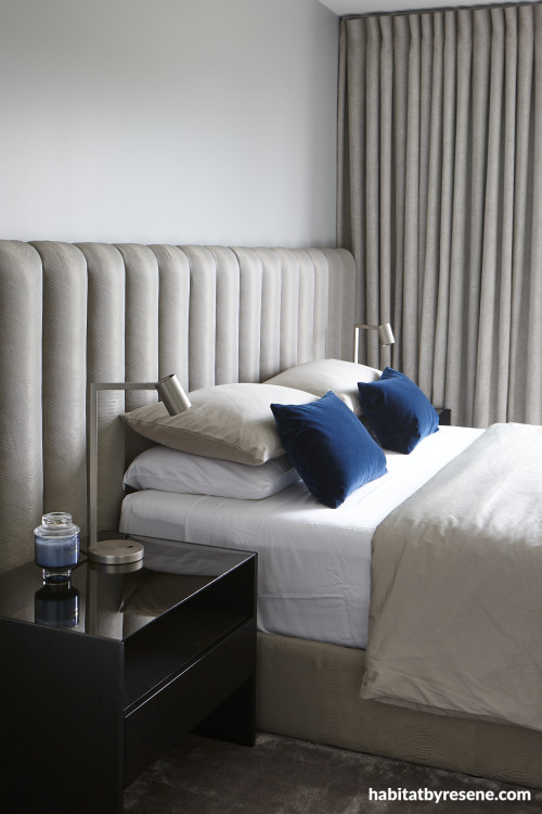 A neutral bedroom with soft drapes and blue pillows