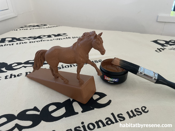 A horse on a doorstop with a paint pot and paintbrush