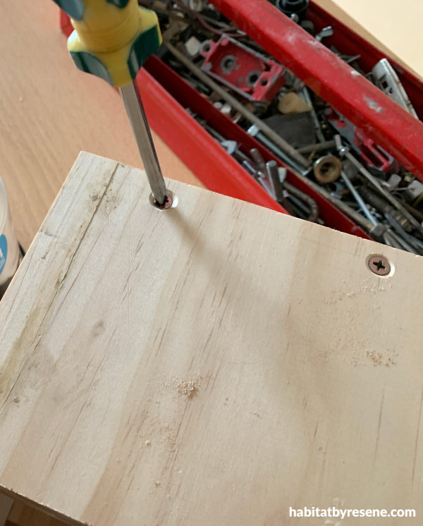 A screwdriver screwing a screw into wood