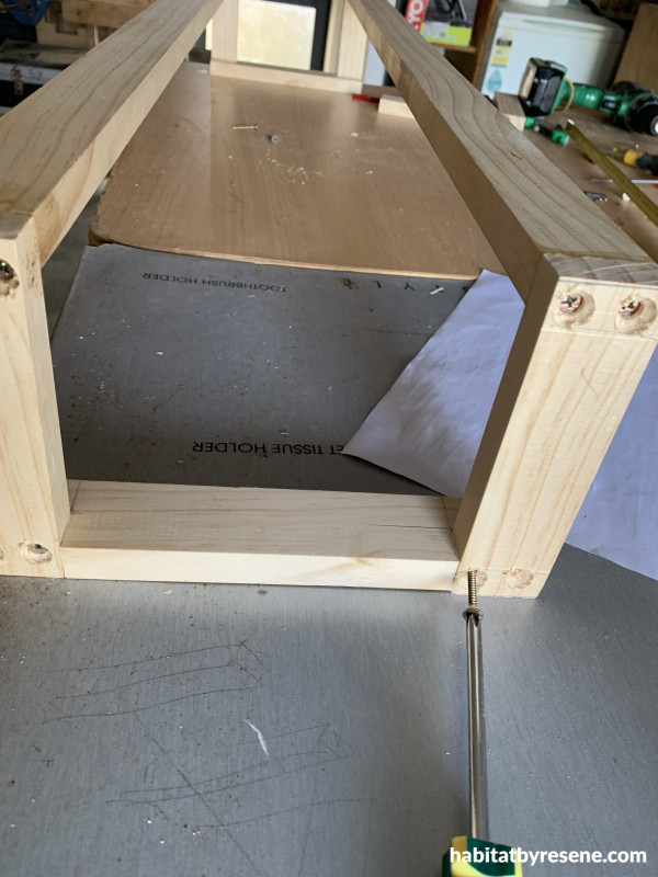 A wooden wall towel holder with a screwdriver screwing in screws