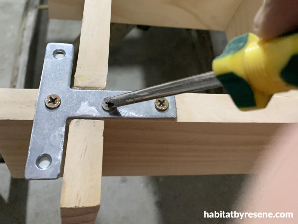 A shelf with a bracket and a screwdriver screwing in a screw