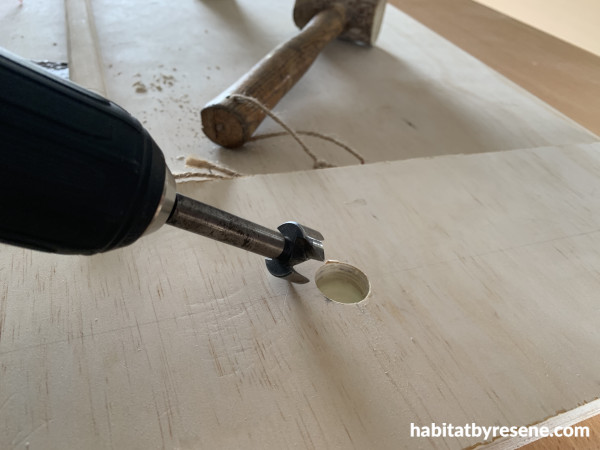 A piece of plywood with a drill and circular hole
