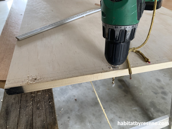 A drill drilling holes into a piece of plywood