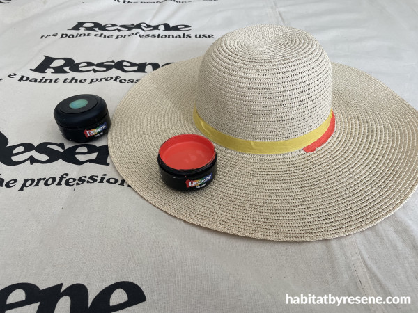 A hat with tape around it and a red pot of paint