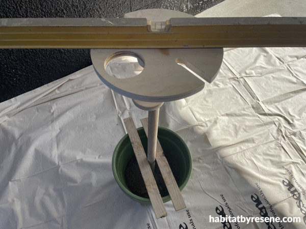 A plant pot with concrete and a wine holder standing in it