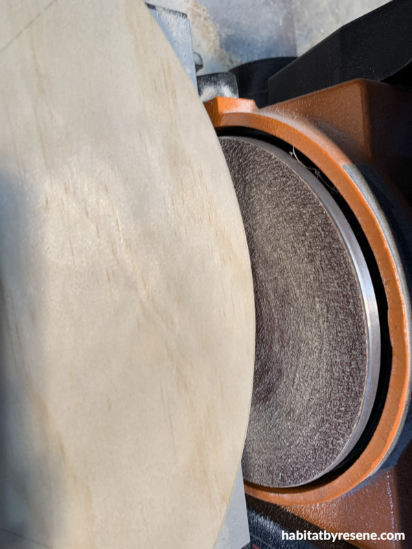 A sander sanding the edge of a piece of wood