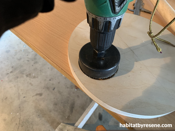 A drill cutting a circle into a piece of wood