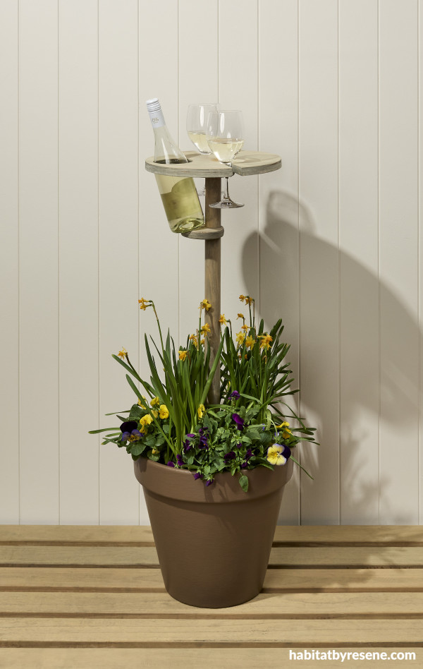 A plant pot with a wine holder and flowers