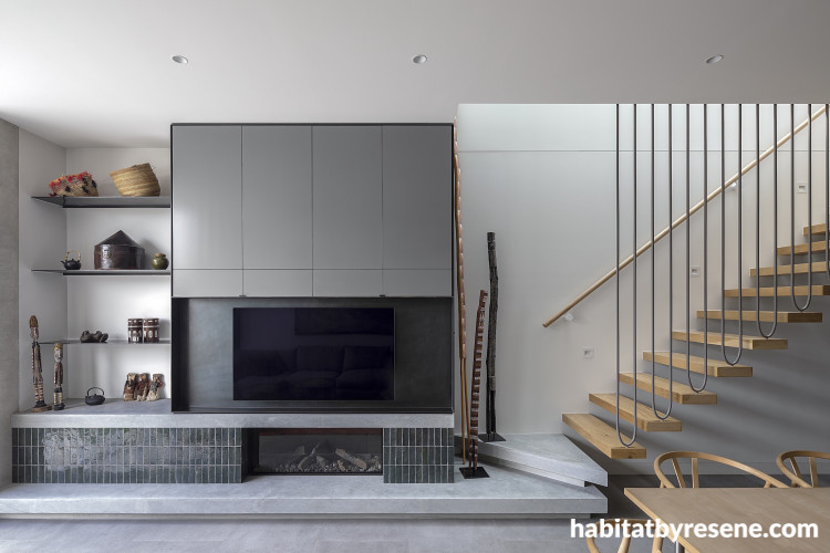 A living space with a large fireplace and wooden stairs