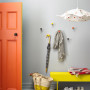 An entry with grey walls, orange door and yellow bench