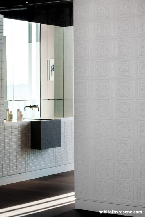 Bathroom featuring tiled vanity and textured wallpaper