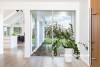entranceway, wood front door, indoor plant, white living area, white house 