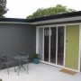 1970s home, house exterior, sleepout, grey exterior, green door, grey sleepout