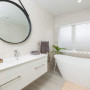 white bathroom, freestanding bath, hanging mirror, white tiles, curved bath 