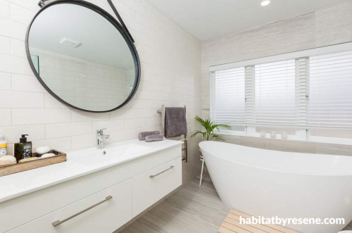 white bathroom, freestanding bath, hanging mirror, white tiles, curved bath
